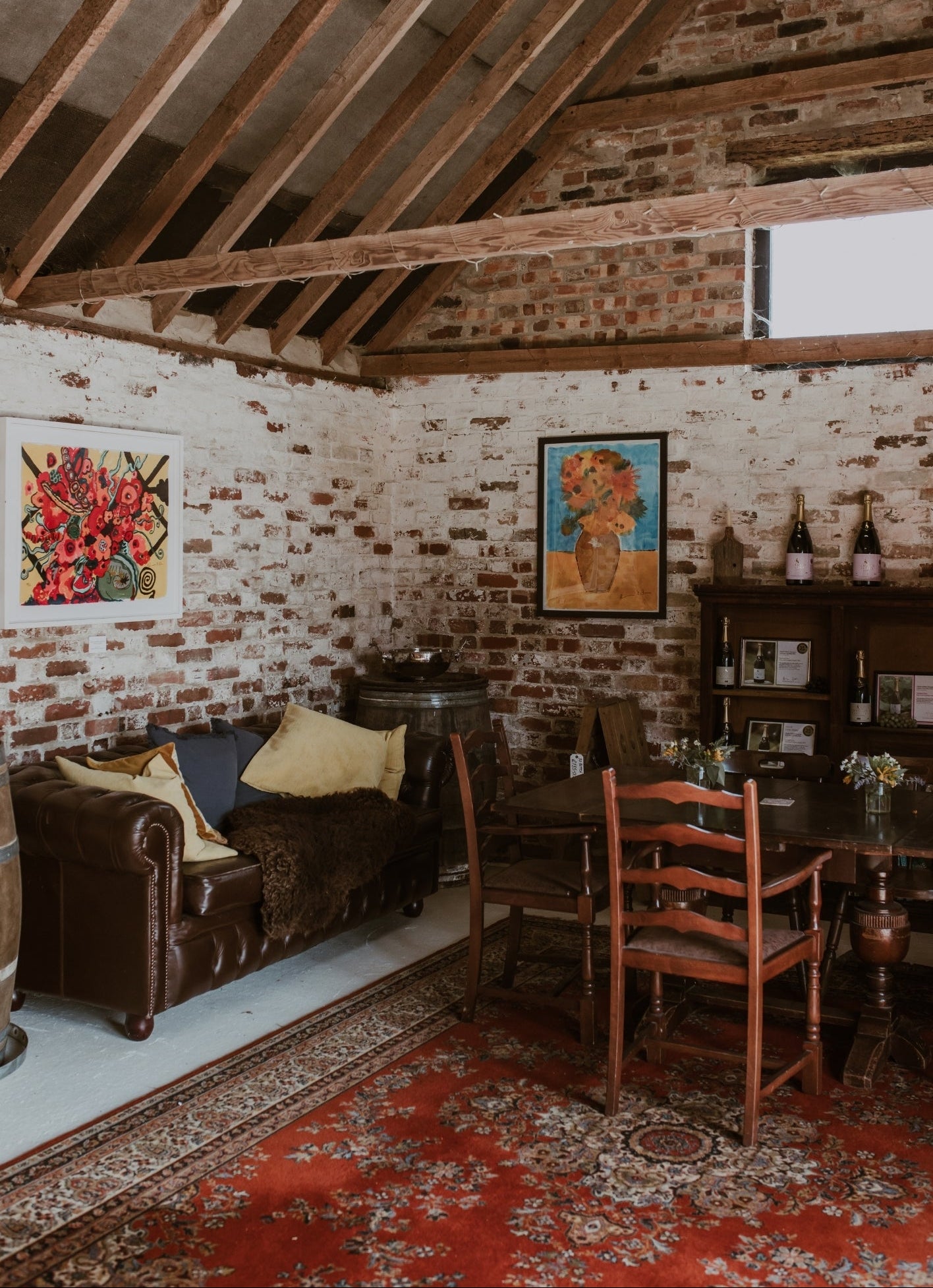 Wine bar lounge with brick walls, wooden beams, and a sofa with cushions