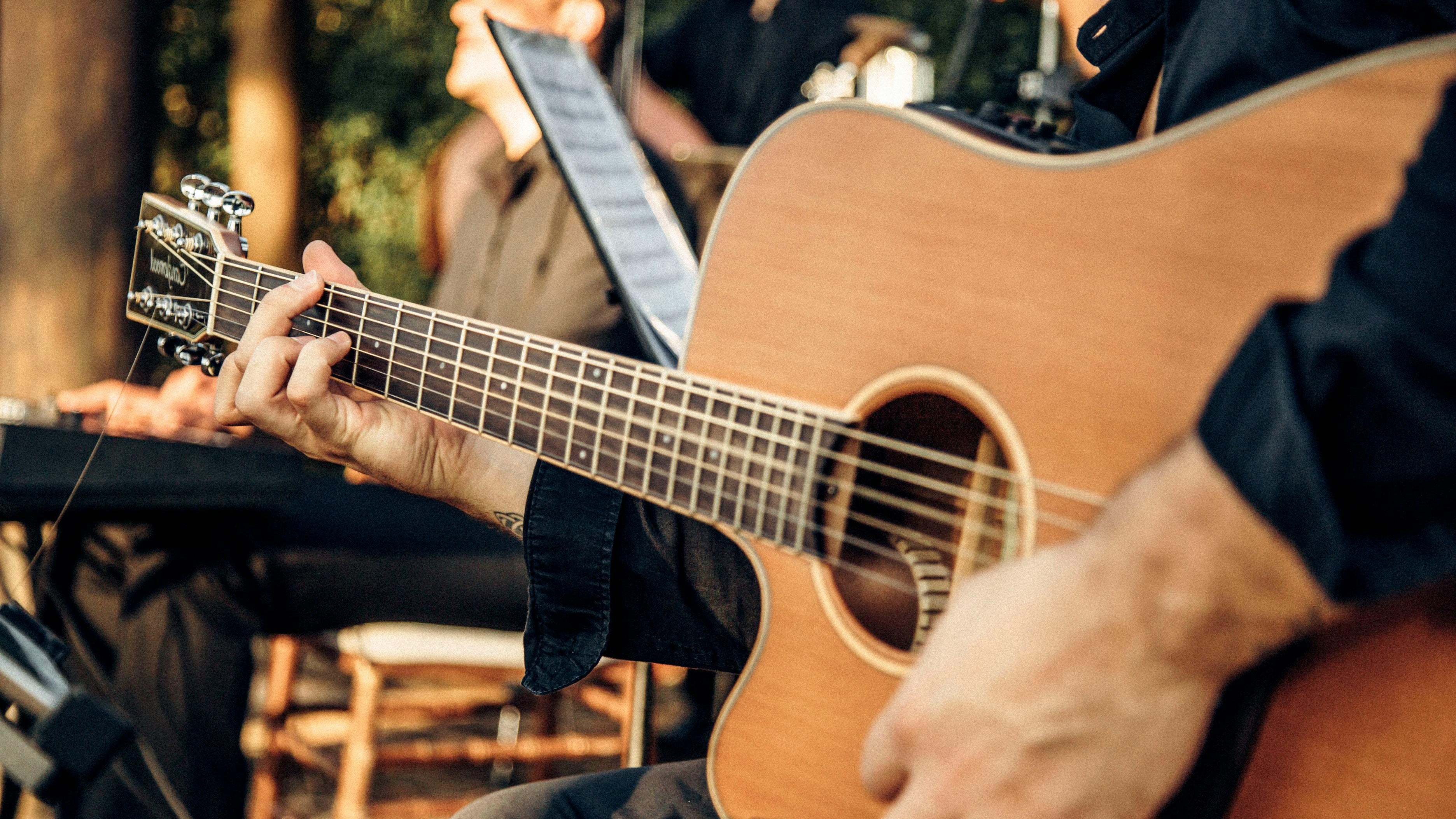 Person playing an acoustic guitar with a blurred background